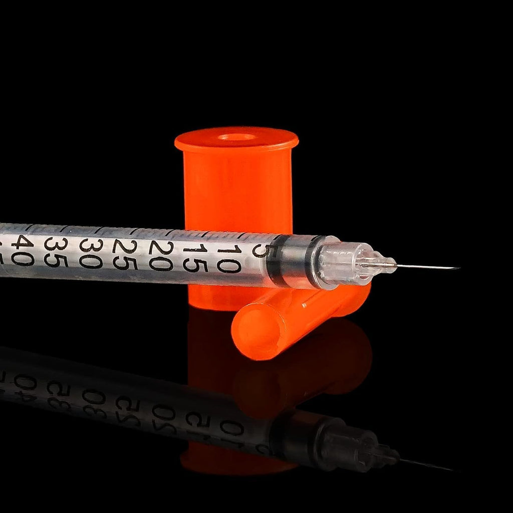 Seringue transparente avec aiguille fine et graduations, capuchon orange sur fond sombre